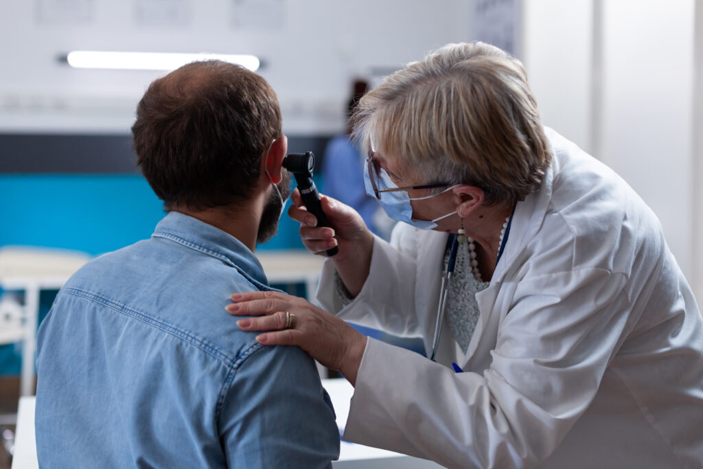 close up physician using otoscope ear consultation with patient woman otologist checking infection with otolaryngology instrument medical visit coronavirus pandemic