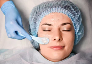 cosmetologist hand applying cosmetic mask woman face