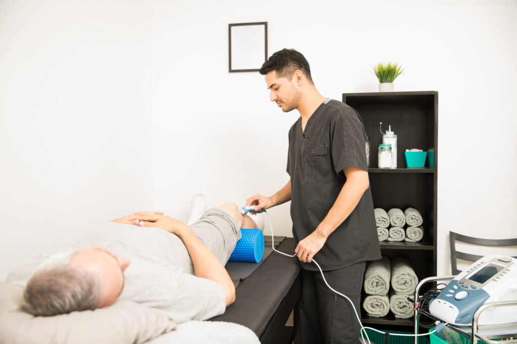 physical therapist using ultrasound probe patient knee while standing hospital