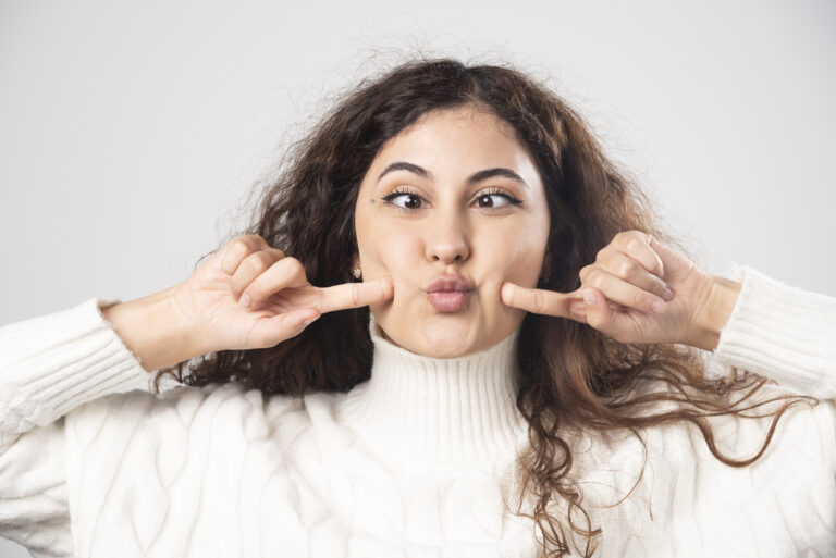 young woman white sweater doing funny face white wall high quality photo